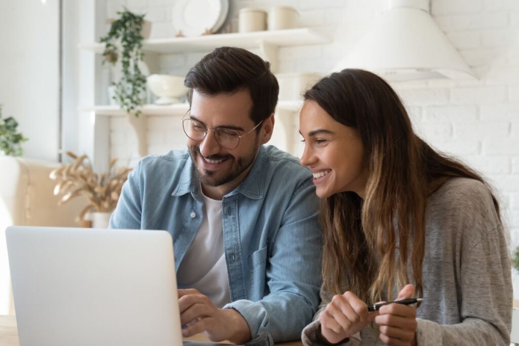 Happy young couple paying bills online in computer app