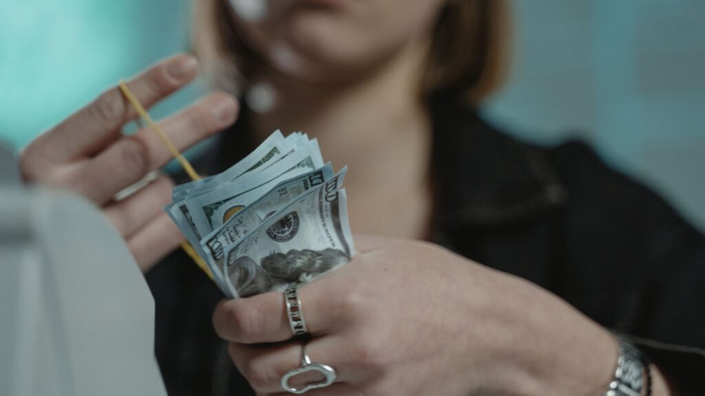 Close-up of a woman counting U.S. dollar bills, wearing rings and a wristwatch.