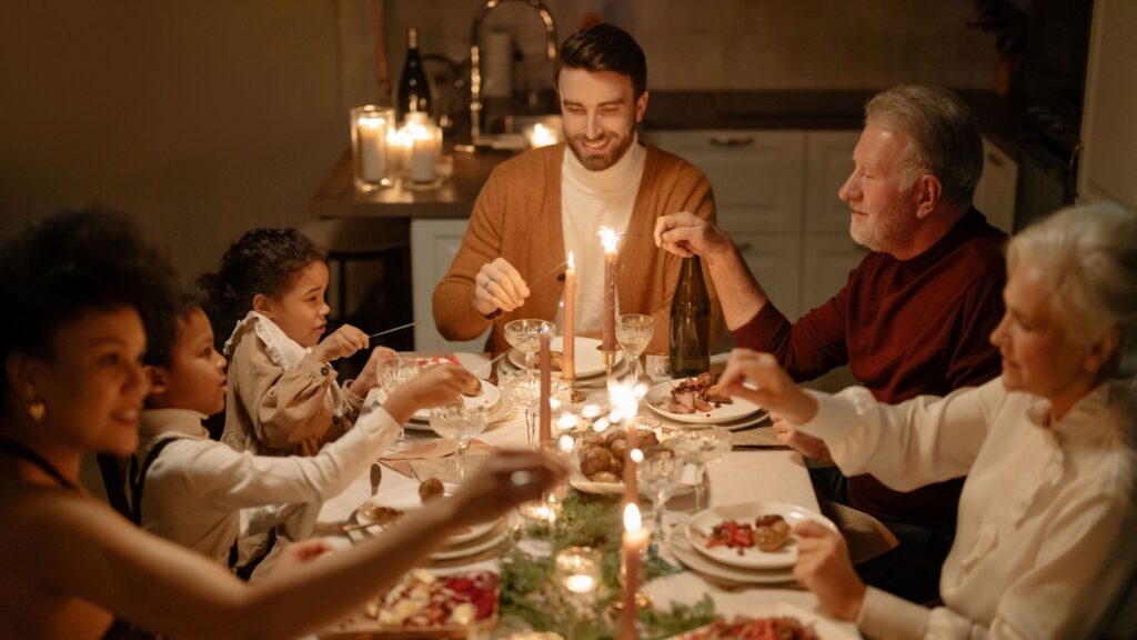 Family enjoying a festive dinner together indoors with warm candlelight.