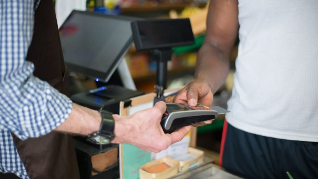 Customer tapping credit card on payment terminal at a small business checkout counter.