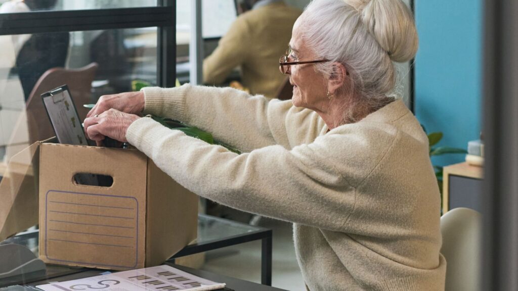 An elderly woman packing up their desk items.