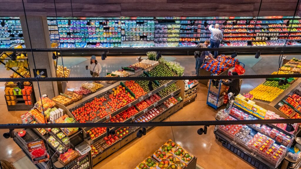 Shoppers in the vegetable and fresh produce section of a grocery store.