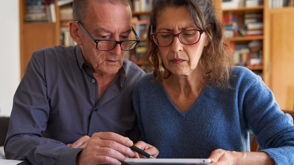 An older couple reviewing financial documents together at home.
