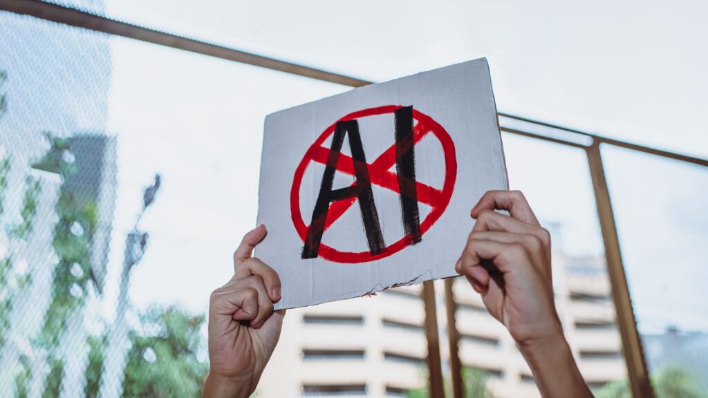 Hands holding a protest sign with AI crossed out in red.