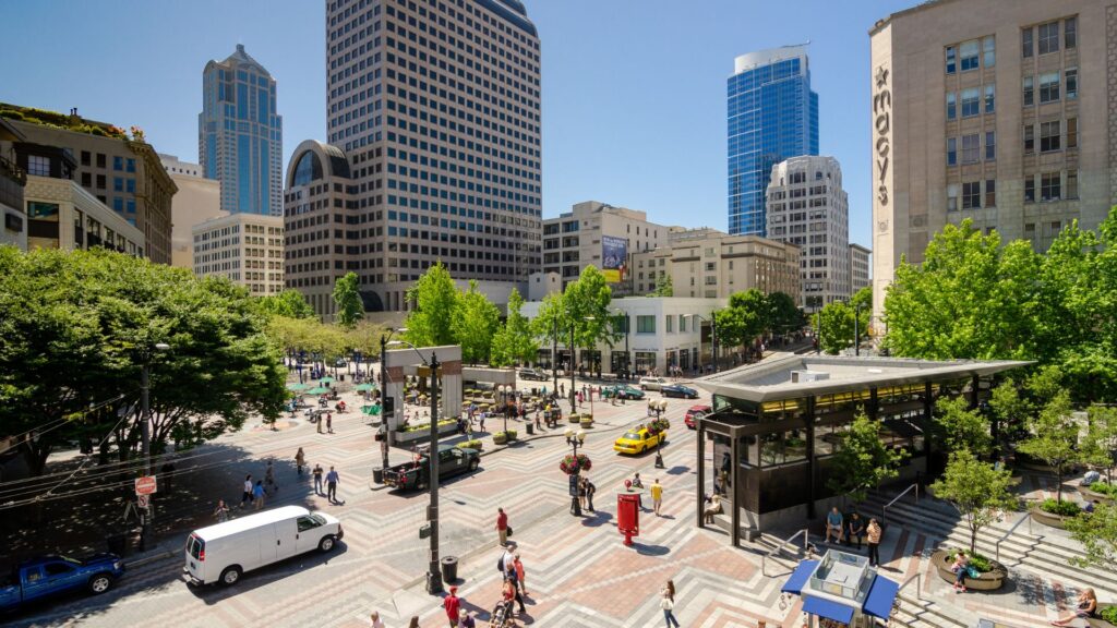Pedestrians and traffic in a busy downtown Seattle plaza.