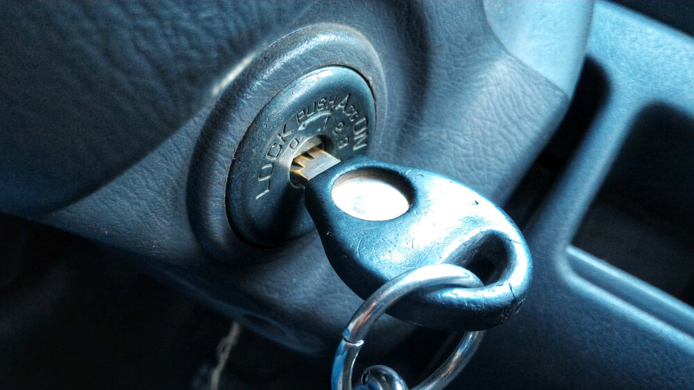 Car key inserted into ignition with lock and push position visible on dashboard.