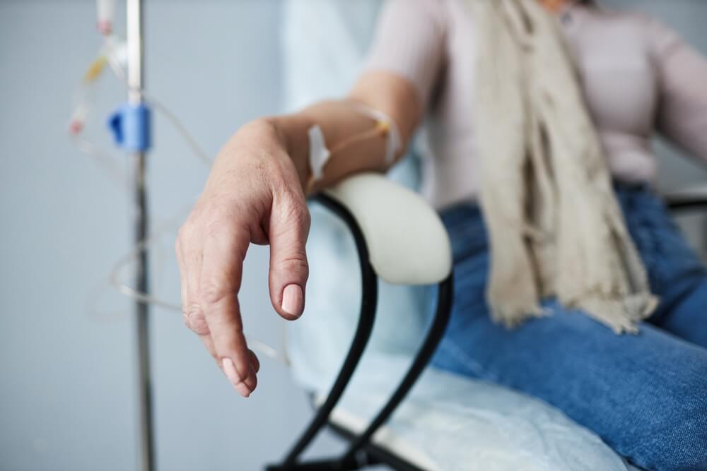 Patient resting in clinic chair with IV drip attached to arm during treatment.